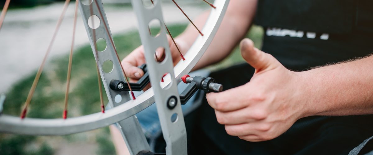 male-person-adjusts-bike-spokes-and-wheel-PCSWBP4